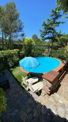 a blue umbrella and chairs next to a swimming pool at Loft Vacarisses Torreblanca Estación, Piscina Privada in Vacarisas