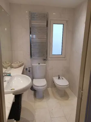 a white bathroom with a toilet and a sink at Cal Duran in Esparreguera