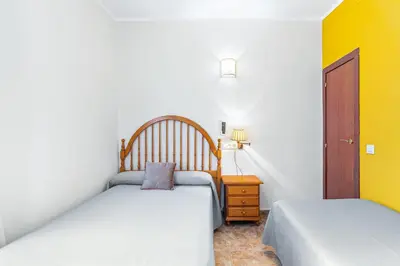 a room with two beds and a yellow wall at Hostal Santa Ana in Barcelona