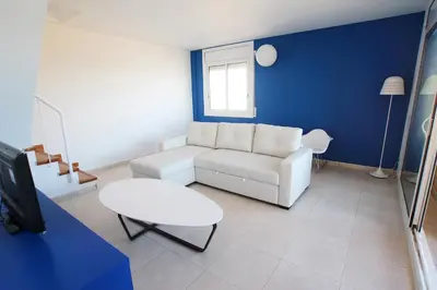 a living room with a white couch and a blue wall at Espectacular ático dúplex con vistas al mar in Cunit
