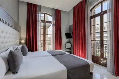 a bedroom with a large bed with red curtains at Hotel Ciutadella Barcelona in Barcelona