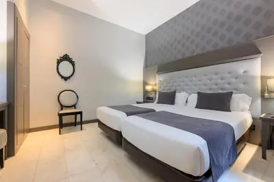 a hotel room with two beds and a mirror at Hotel Ciutadella Barcelona in Barcelona