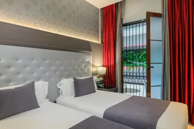 two beds in a hotel room with red curtains at Hotel Ciutadella Barcelona in Barcelona