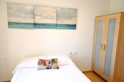 a bedroom with a white bed with a painting on the wall at Homenfun Barcelona Plaza España in Barcelona