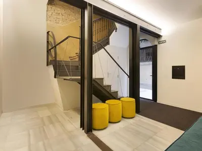 a hallway with a staircase and yellow stools at Decô Apartments Barcelona-Born Apt. in Barcelona