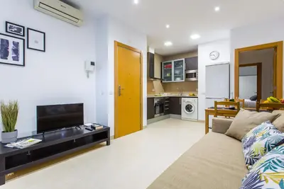 a living room with a couch and a tv and a kitchen at Feriapiso Apartments Palmer in Hospitalet de Llobregat