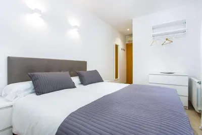 a bedroom with a large bed with a blue blanket at Feriapiso Apartments Palmer in Hospitalet de Llobregat