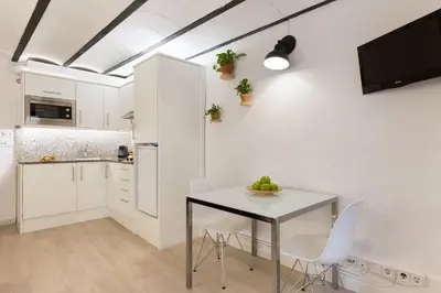 a kitchen with white cabinets and a table and chairs at Ola Living Born in Barcelona
