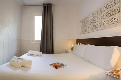 a bedroom with a large white bed with towels on it at Enjoybcn Gaudi Apartments in Barcelona