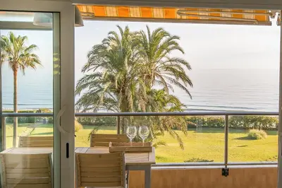 a dining room with a view of the ocean and palm trees at GAVA4 BEACHFRONT Apartment BARCELONA in Gavà