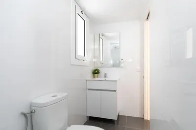 a white bathroom with a toilet and a sink at Key Barcelona HOUSING (Carrer Girona) in Barcelona