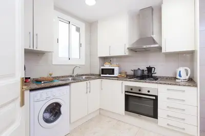 a kitchen with white cabinets and a washer and sink at Key Barcelona HOUSING (Carrer Girona) in Barcelona
