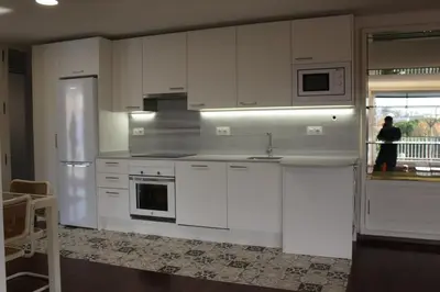 a kitchen with white cabinets and a person standing in the window at Apartamento con piscina cerca de Barcelona in Masnou