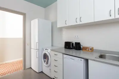 a white kitchen with a washing machine and a sink at Casa Cosi - Mallorca 2 in Barcelona