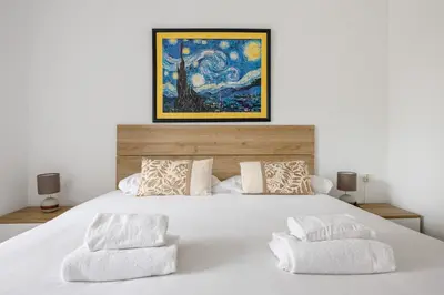 a bedroom with a white bed with a painting on the wall at Besos · Bright apartment close to congress & port in Sant Adria de Besos
