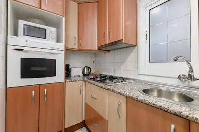 a kitchen with wooden cabinets and a sink and a microwave at Besos · Bright apartment close to congress & port in Sant Adria de Besos