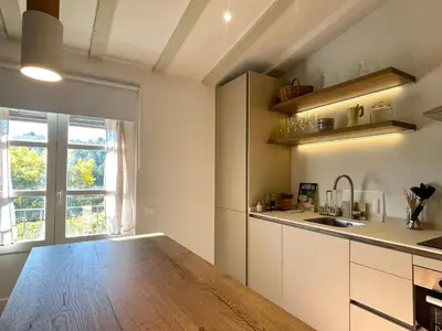 a kitchen with white cabinets and a wooden table at Comarquinal Bioresort Penedes in San Quintín de Mediona