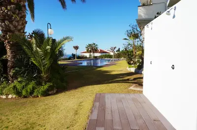 a walkway leading to a swimming pool with palm trees at Cala Balmins Sea View in Sitges