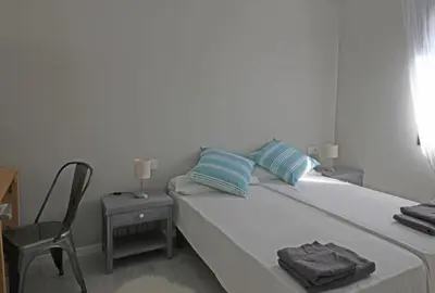 a bedroom with a bed with blue pillows and a chair at Fridays Flats Casa Lemonade in Hospitalet de Llobregat