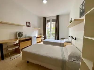 a hotel room with two beds and a desk and a desk at Barcelona Housing recommend for Students in Barcelona