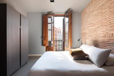 a bedroom with a large bed with a brick wall at DestinationBCN Universitat Apartments in Barcelona