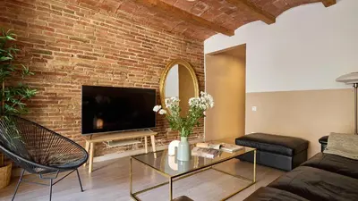 a living room with a brick wall and a tv at Casa Cosi - Mallorca 3 in Barcelona