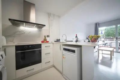 a white kitchen with a sink and a dishwasher at Aparthotel Marsol in Castelldefels