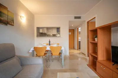 a kitchen and living room with a table and chairs at Aparthotel Marsol in Castelldefels