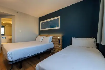 two beds in a small room with blue walls at Travelodge Barcelona Poblenou in Barcelona