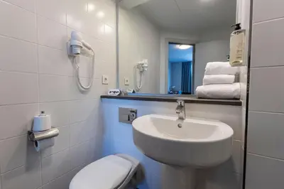 a bathroom with a sink and a toilet and a mirror at Travelodge Barcelona Poblenou in Barcelona