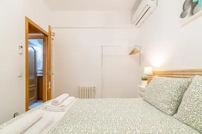 a white bedroom with a bed and a mirror at Confort Barcelona Rentals in Barcelona
