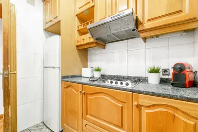 a kitchen with wooden cabinets and a stove top oven at Confort Barcelona Rentals in Barcelona