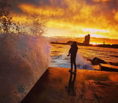 a person riding a skateboard in front of the water at Rambla Poblenou&Mar Bella Beach in Barcelona