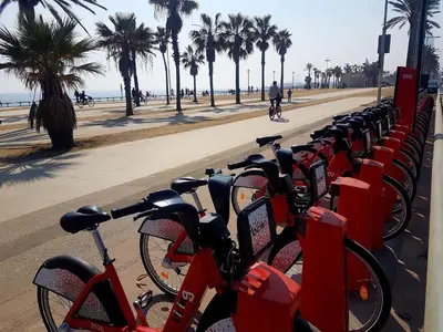 a row of red bikes parked next to a beach at Rambla Poblenou&Mar Bella Beach in Barcelona