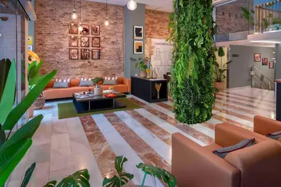 a living room with orange couches and plants at SERHS Carlit Boutique Hotel in Barcelona