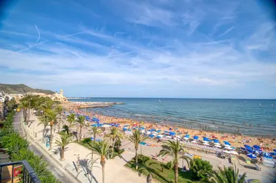 a beach with umbrellas and people on the water at Blue sea front by Hello Homes Sitges in Sitges