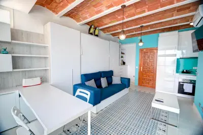 a living room with a blue couch and a kitchen at Blue sea front by Hello Homes Sitges in Sitges