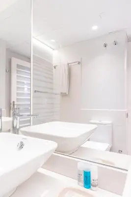 a white bathroom with two sinks and a mirror at Serennia Fira Gran Via Exclusive Rooms in Hospitalet de Llobregat
