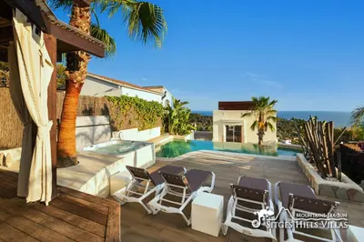 a villa with a swimming pool and palm trees at Stunning Villa Ibizenca with private pool in Sitges in Sitges
