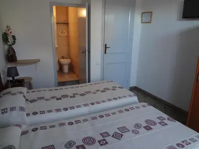 two beds in a room with a bathroom at Hostal Sant Carlo in Barcelona
