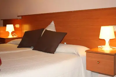 a hotel room with two beds with two lamps at PENSIÓN Colmenero in Barcelona