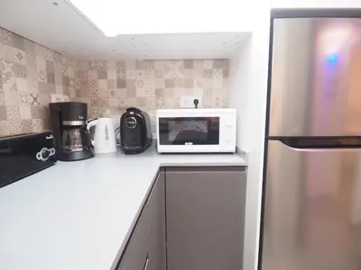 a kitchen counter with a microwave and a refrigerator at Balcony View Apartment by Hello Homes Sitges in Sitges