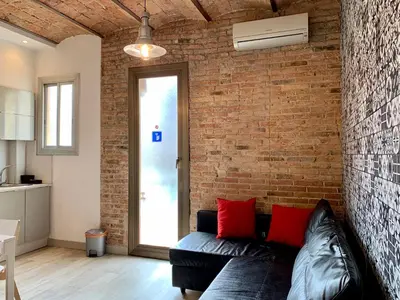 a living room with a black couch and a brick wall at Charm Miró in Barcelona