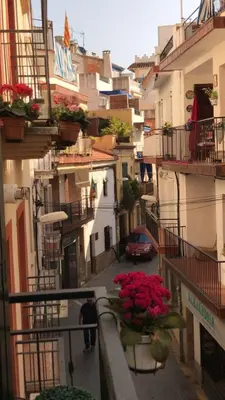 an alley with flags and people walking down a street at Casa Susana in Sitges