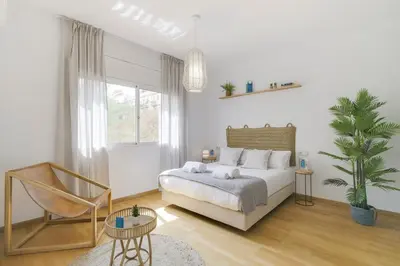 a white bedroom with a bed and a chair at Sweett - Monumental in Barcelona