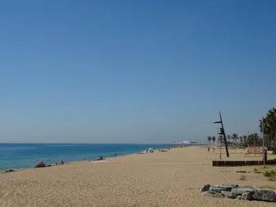 a beach with people laying on the sand and the ocean at Duplex en frente de la playa al lado de Barcelona in Canet de Mar