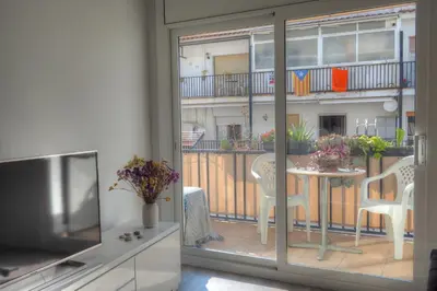 a living room with a balcony with a table and a television at Orquidea Apartment by Hello Homes Sitges in Sitges