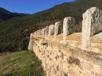 a stone wall with a mountain in the background at Masia de Vallforners in Tagamanent
