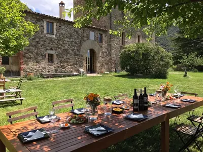 a wooden table with wine bottles and glasses in a yard at Masia de Vallforners in Tagamanent