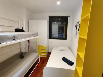 a small room with two beds and yellow shelves at Barcelona-Forum Apartments in Barcelona